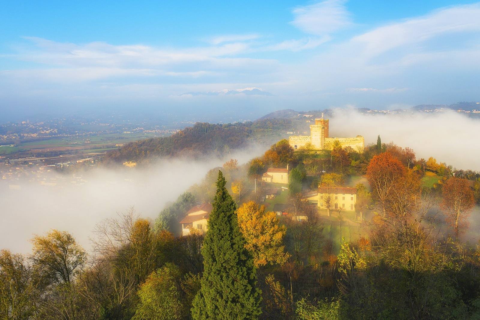 One of Montecchio’s castles rising above autumn trees and a sea of fog over the plain