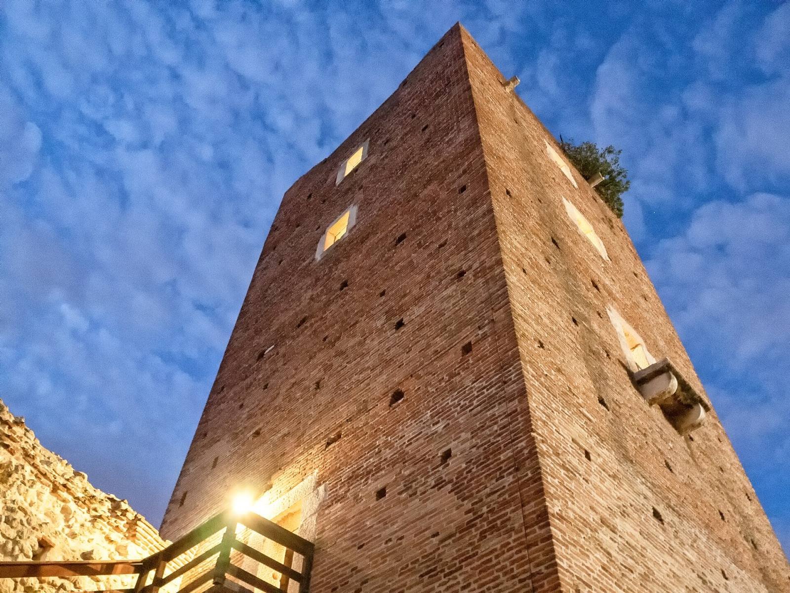The tall tower of Juliet’s Castle lit at dusk under a blue sky