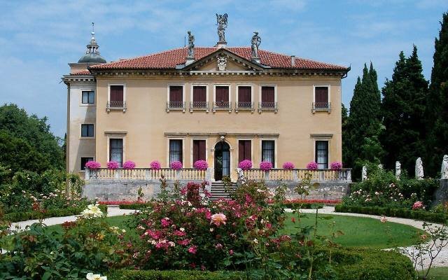 The pale front of Villa Valmarana ai Nani behind a garden of roses