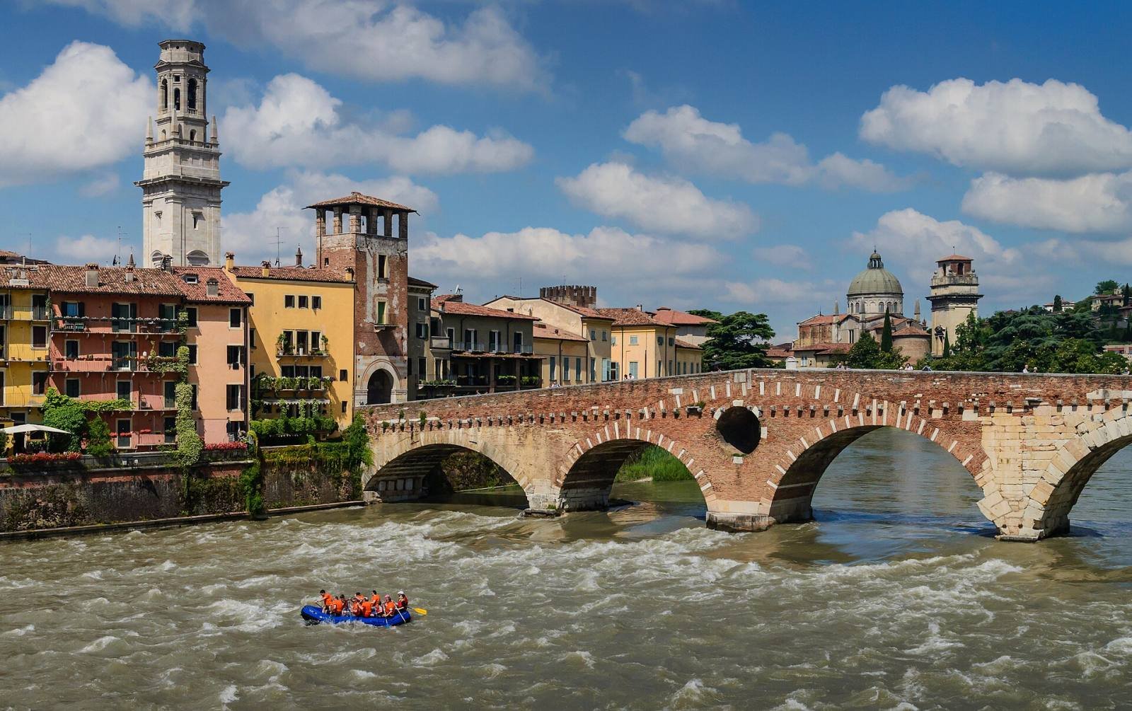 The Ponte Pietra bridge over the rushing Adige river in Verona, with a bell tower behind