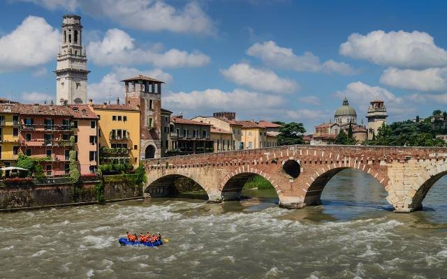 The Ponte Pietra bridge over the rushing Adige river in Verona, with a bell tower behind