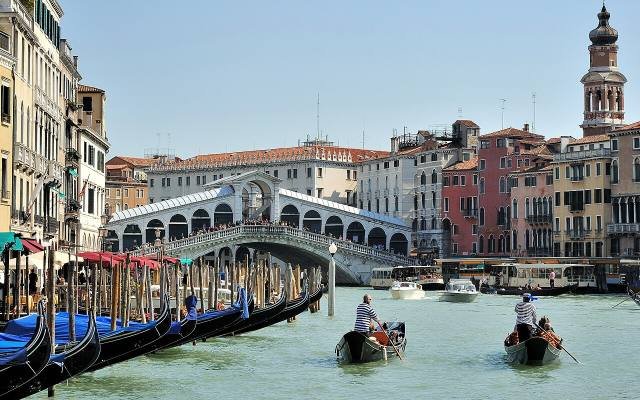 Gondoliers rowing passengers on the Grand Canal by the Rialto Bridge in Venice